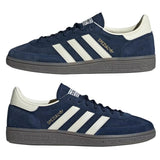 Navy blue Adidas sneakers with white stripes on a light gray background